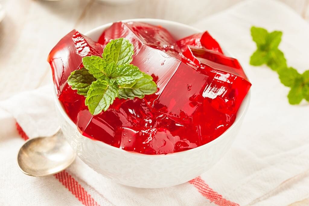 Red jelly in white bowl with the mint over it