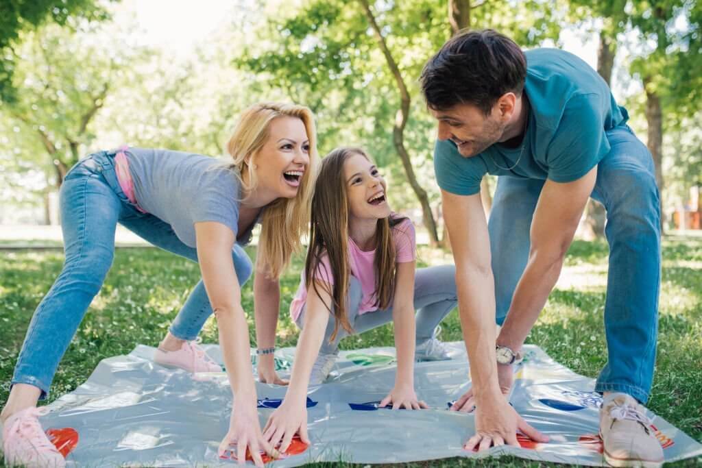 kid playing twister with parents in park